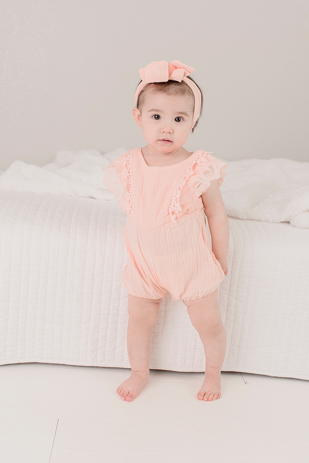 Baby girl with a pink bow during her light and airy studio session | Photo by Jessica Lee Photography