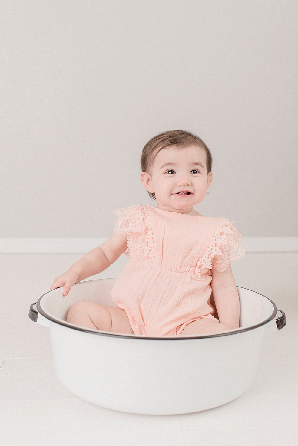 Baby girl in pink dress sitting in a bowl | Photo by Jessica Lee Photography