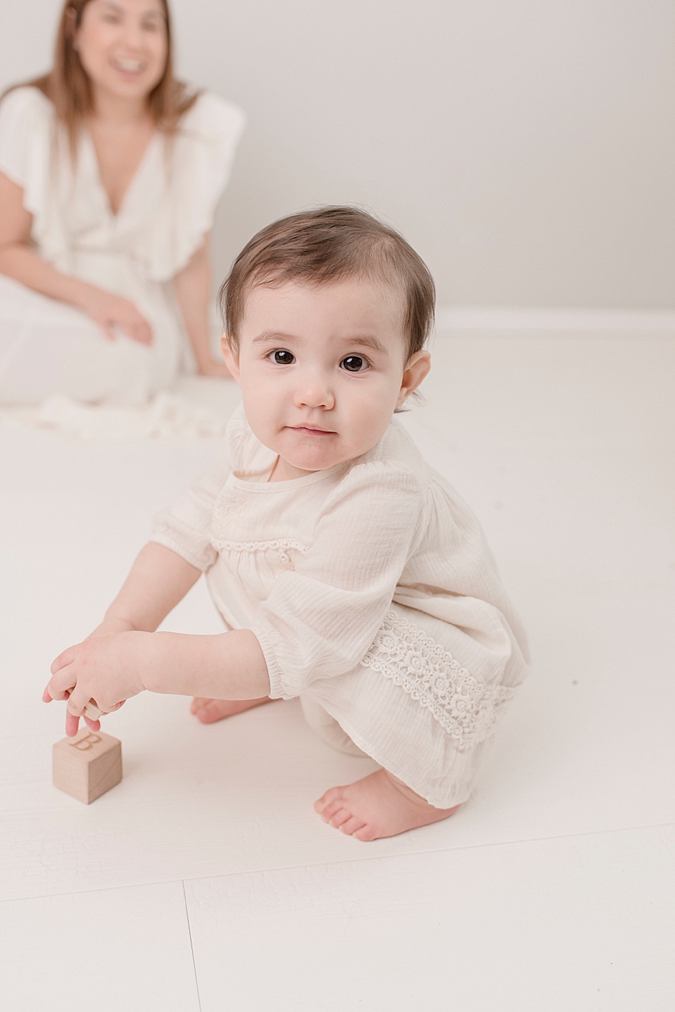 Baby girl in white playing with wooden blocks | Photo by Jessica Lee Photography